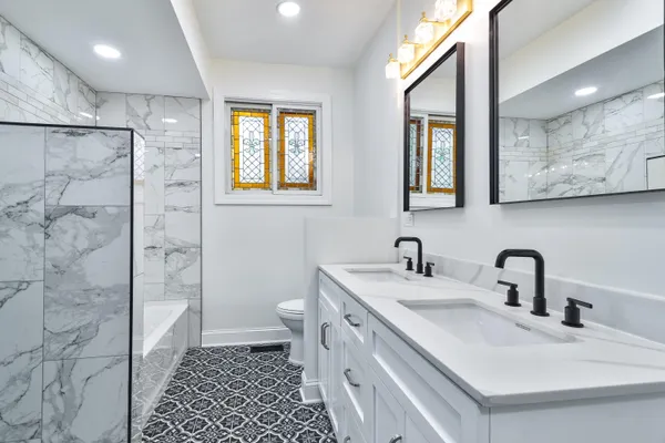 a bathroom with a double vanity sink a toilet and a shower