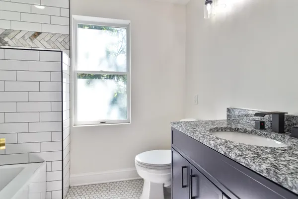 a bathroom with a granite countertop sink toilet and mirror