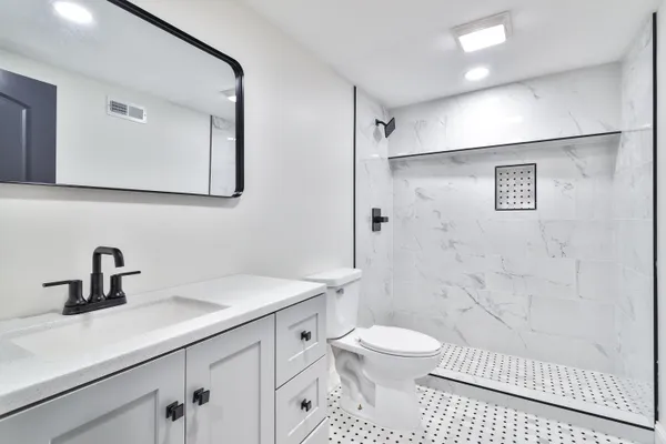 a bathroom with a sink a toilet and shower