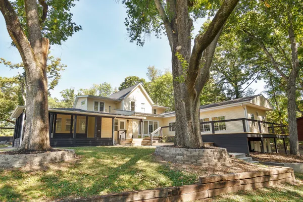 a view of a yard in front of a house with large tree