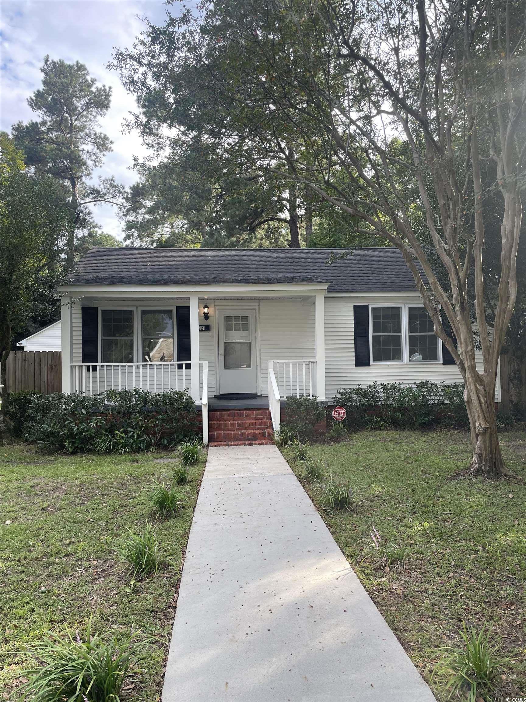 View of front of house featuring a front lawn, a porch, and a shingled roof