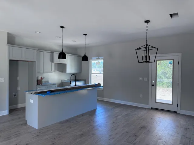 a kitchen with stainless steel appliances granite countertop a sink a window and wooden floor