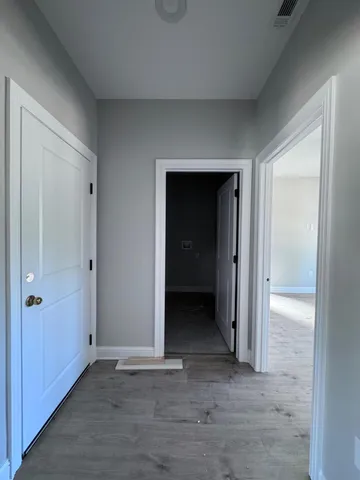 a view of an empty room with closet and wooden door