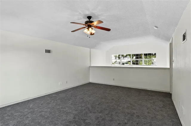 an empty room with windows and fan
