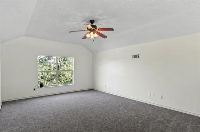an empty room with windows and chandelier fan