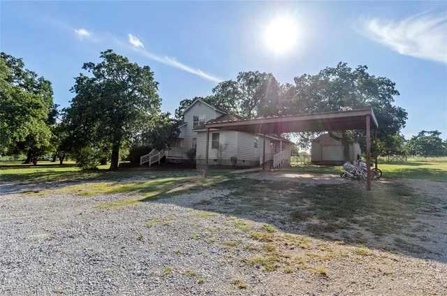 a view of a house with a yard and a large tree