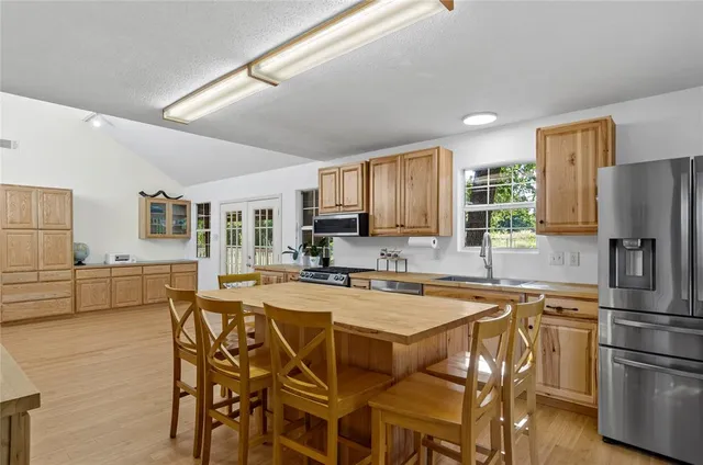a kitchen with stainless steel appliances granite countertop a dining table chairs refrigerator and sink