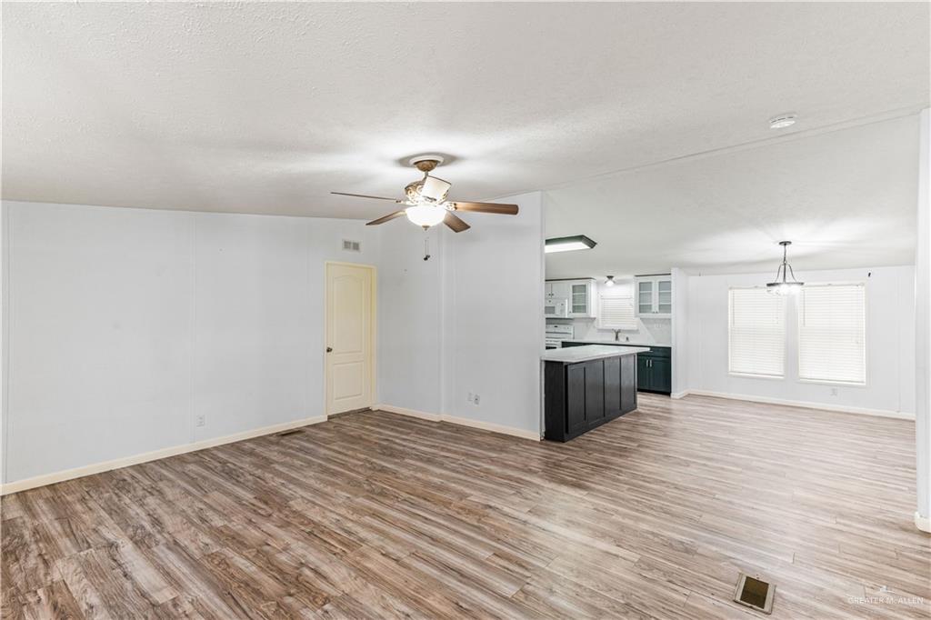 215 South Valley View Road, Unit 252 Donna, TX 78537 - Photo 4 of 19 Spacious open-concept interior featuring wood-finish flooring, a ceiling fan, and white walls