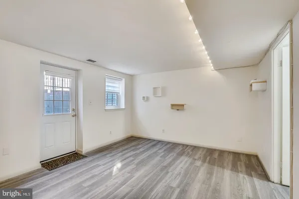 an empty room with wooden floor and windows