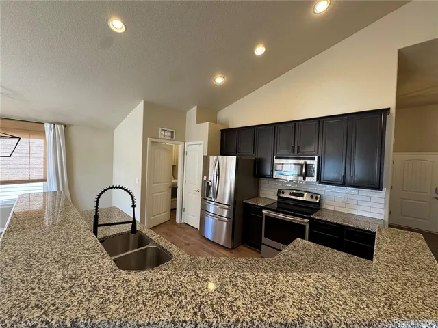 a kitchen with stainless steel appliances granite countertop a stove a sink and a refrigerator