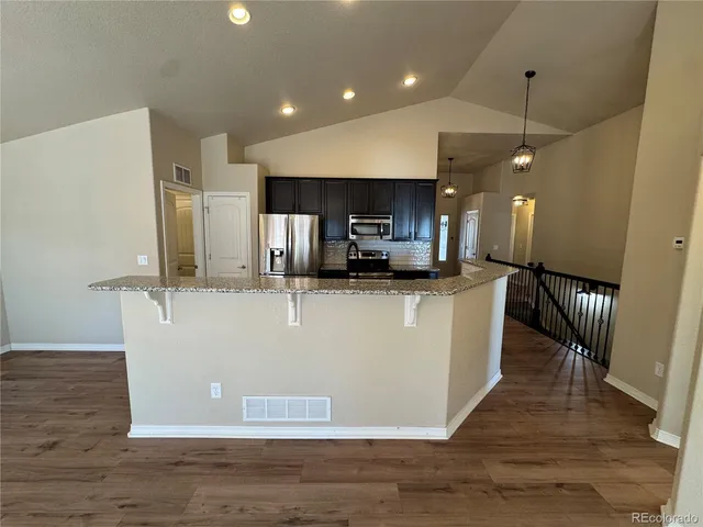 a view of a kitchen with kitchen island stainless steel appliances refrigerator stove microwave and cabinets