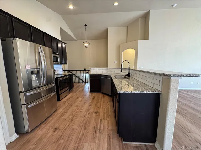 a kitchen with granite countertop stainless steel appliances a sink and refrigerator