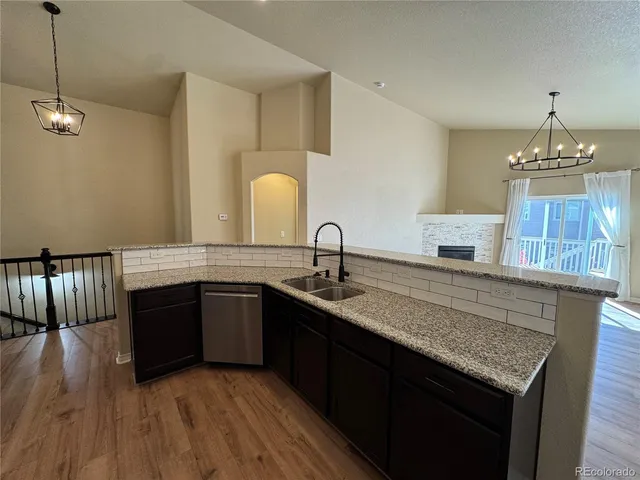 a kitchen with stainless steel appliances granite countertop a sink dishwasher a stove and a refrigerator with wooden floor