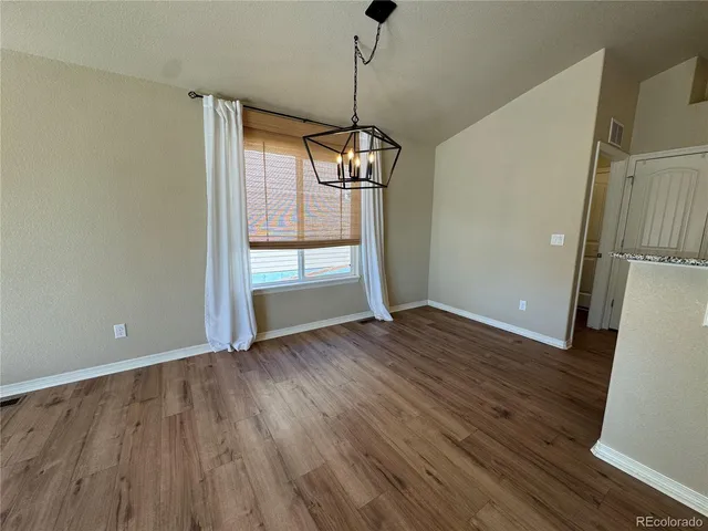 a view of empty room with wooden floor and window
