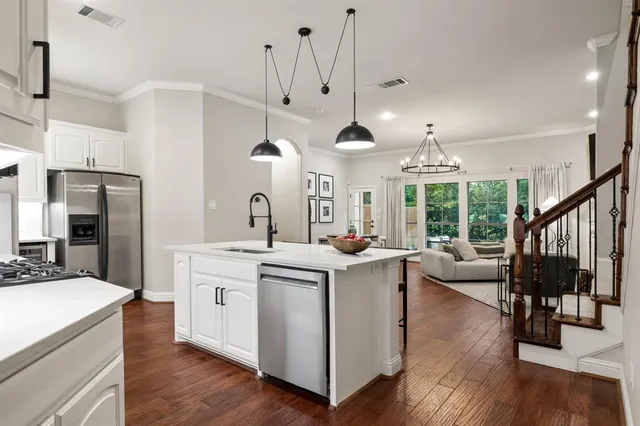 a kitchen with stainless steel appliances kitchen island a dining table chairs and a chandelier