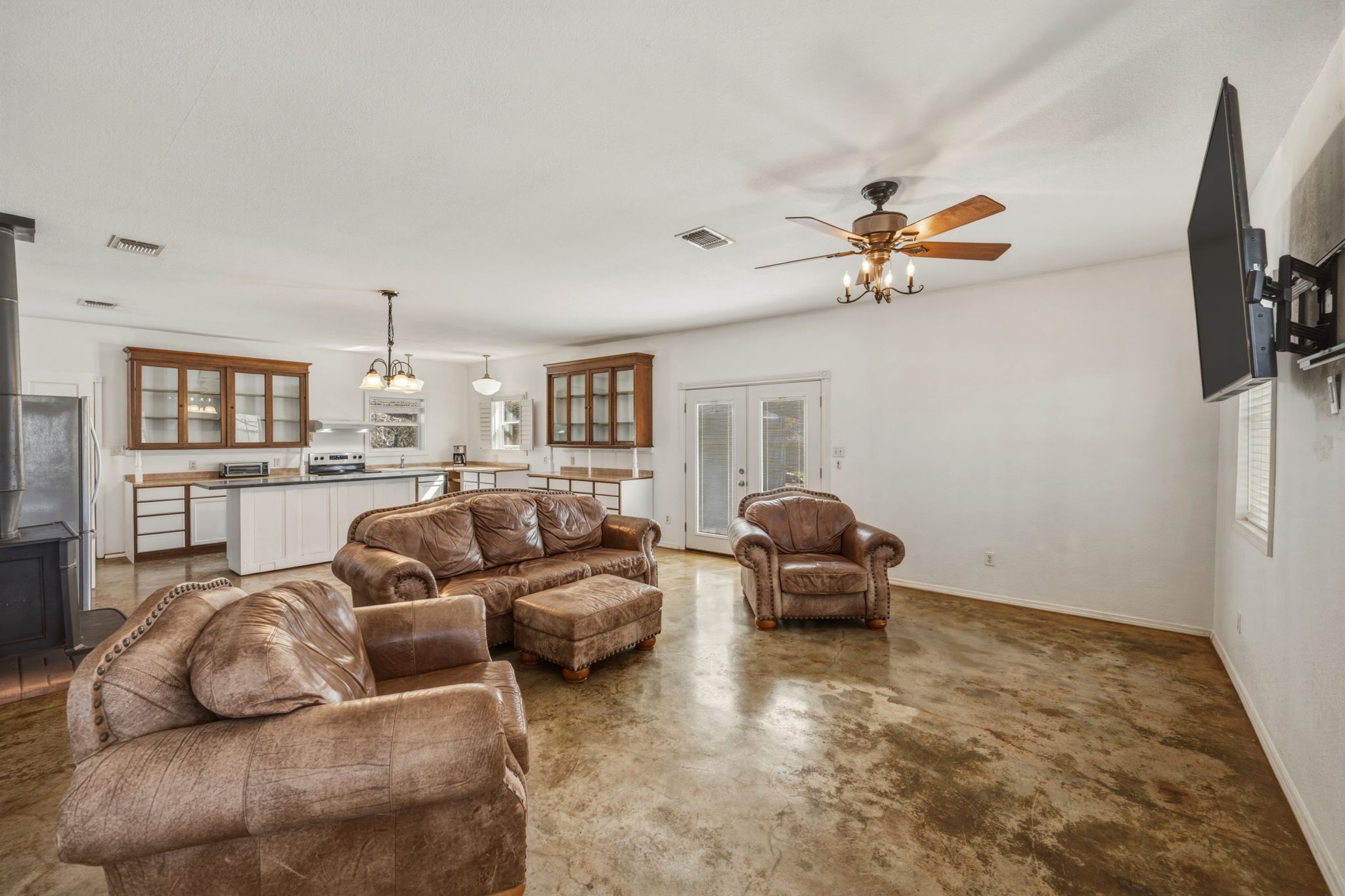 1301 Altwein Road Blanco, TX 78606 - Photo 11 of 40 Living area featuring concrete floors, hanging lights, a ceiling fan, and french doors