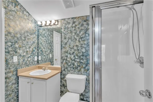 a bathroom with a sink a toilet a mirror and shower