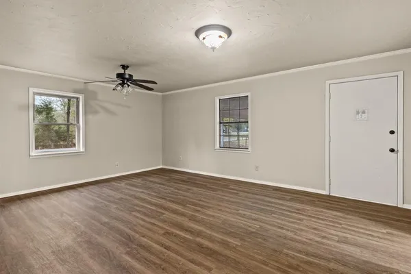 a view of an empty room with a window and a dresser