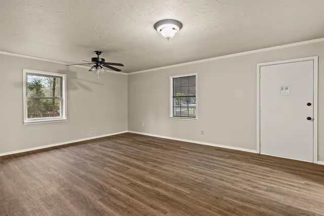 a view of an empty room with a window and a dresser