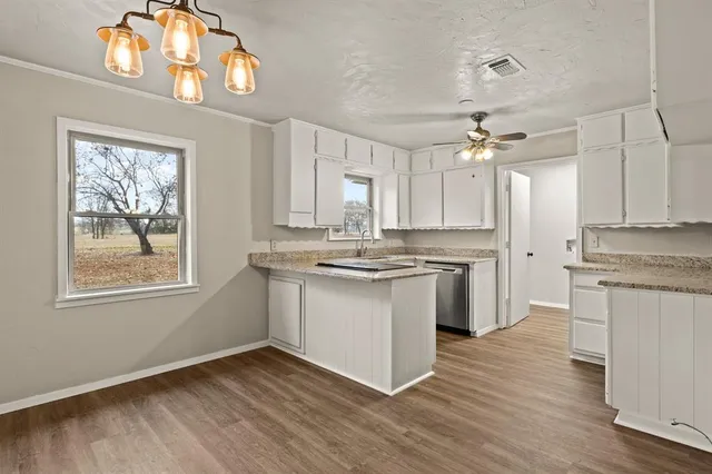 a kitchen with stainless steel appliances granite countertop a stove a sink dishwasher and a refrigerator with wooden floor