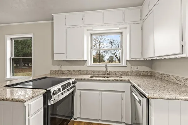 a kitchen with granite countertop a sink stove and cabinets