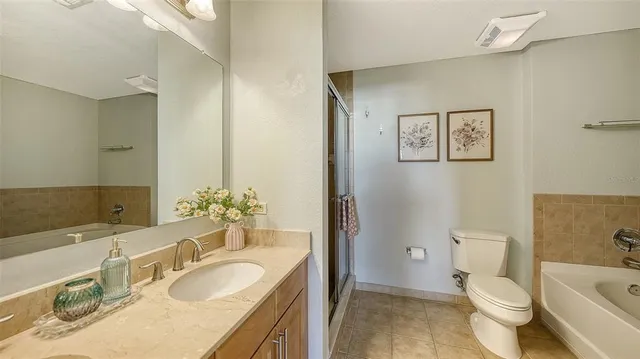 a bathroom with a granite countertop toilet a sink and a large mirror