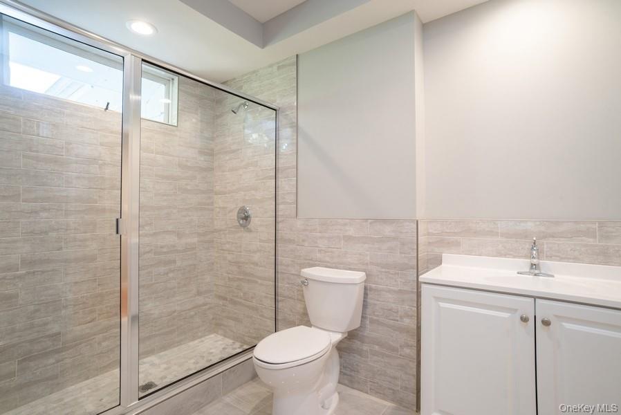 17 Vista Drive Great Neck, NY 11021 - Photo 12 of 20 Full bathroom with vanity, a tile shower, tile walls, wainscoting, and recessed lighting