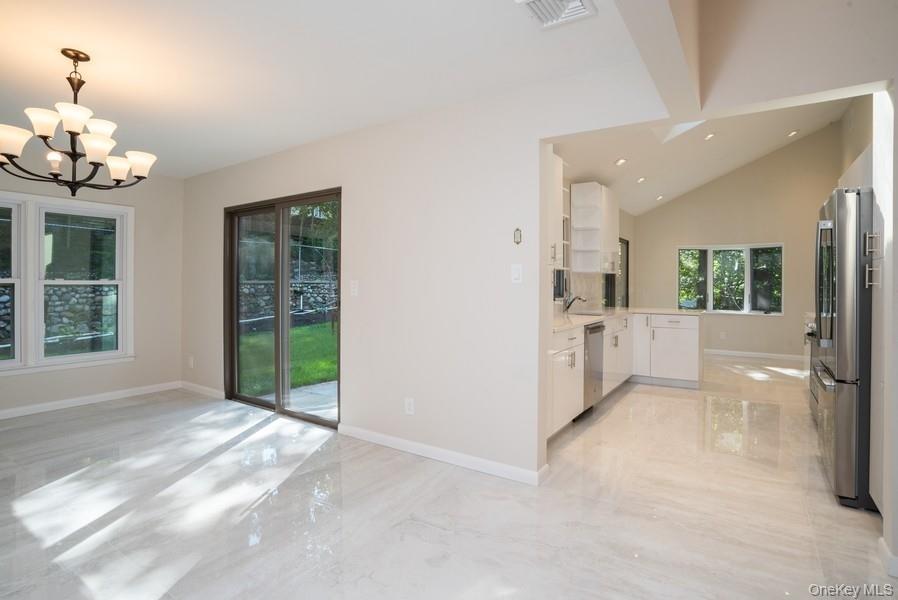 17 Vista Drive Great Neck, NY 11021 - Photo 3 of 20 Kitchen with stainless steel appliances, white cabinetry, light countertops, light marble finish flooring, and a chandelier