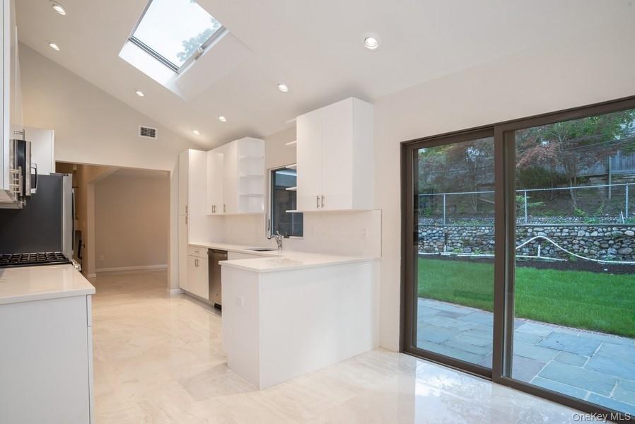 17 Vista Drive Great Neck, NY 11021 - Photo 6 of 20 Kitchen with open shelves, light countertops, white cabinets, appliances with stainless steel finishes, and a skylight
