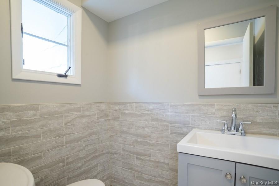 17 Vista Drive Great Neck, NY 11021 - Photo 9 of 20 Bathroom featuring tile walls, vanity, and wainscoting