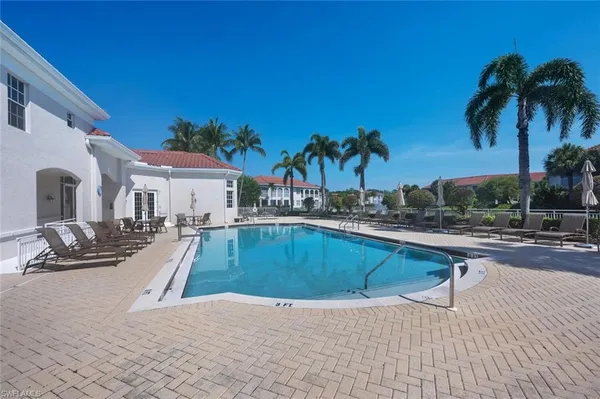 a view of a swimming pool with a lounge chair and palm trees