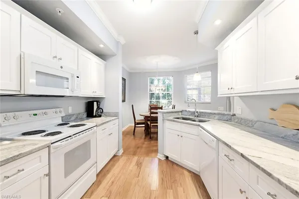 a kitchen with white cabinets appliances and a window