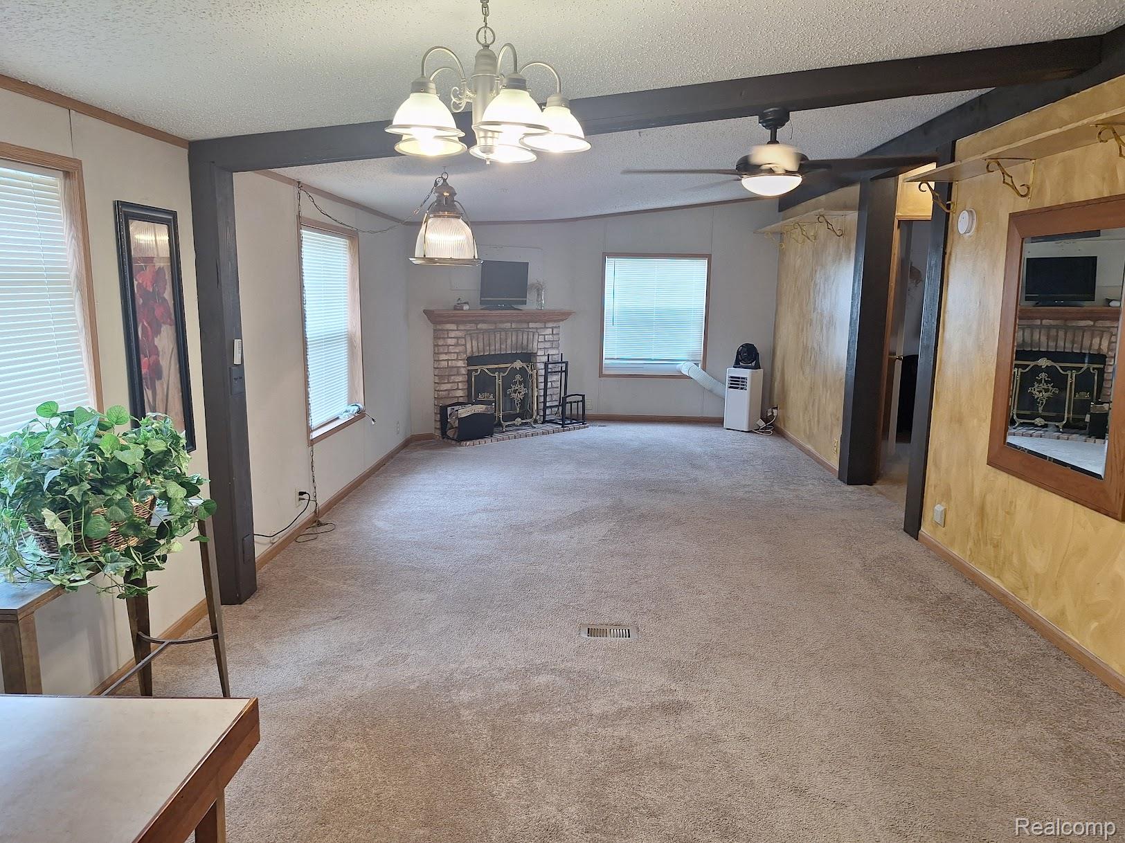 2500-mann Rd Mann Road Clarkston, MI 48346 - Photo 3 of 22 Open concept living space featuring neutral carpeting and a brick-surround fireplace with a hearth