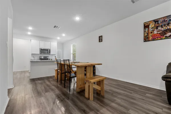 a kitchen with stainless steel appliances a dining table chairs microwave and sink
