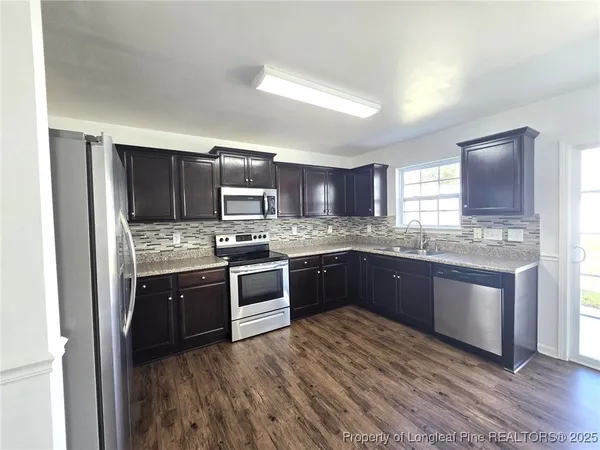 a large kitchen with wooden floors and stainless steel appliances