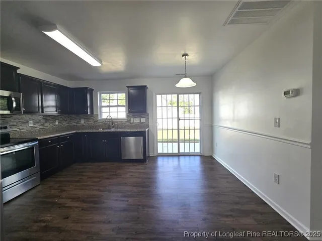 a large kitchen with granite countertop a refrigerator and a stove top oven