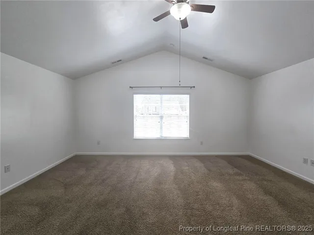 an empty room with a chandelier fan and windows