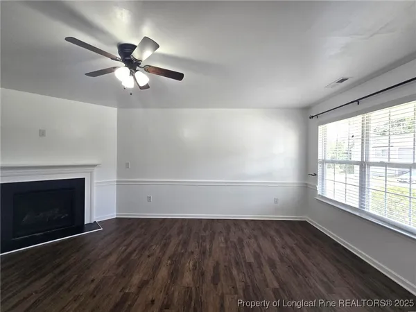 an empty room with wooden floor fan and windows