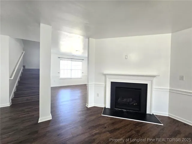 a view of an empty room with wooden floor fireplace and a window