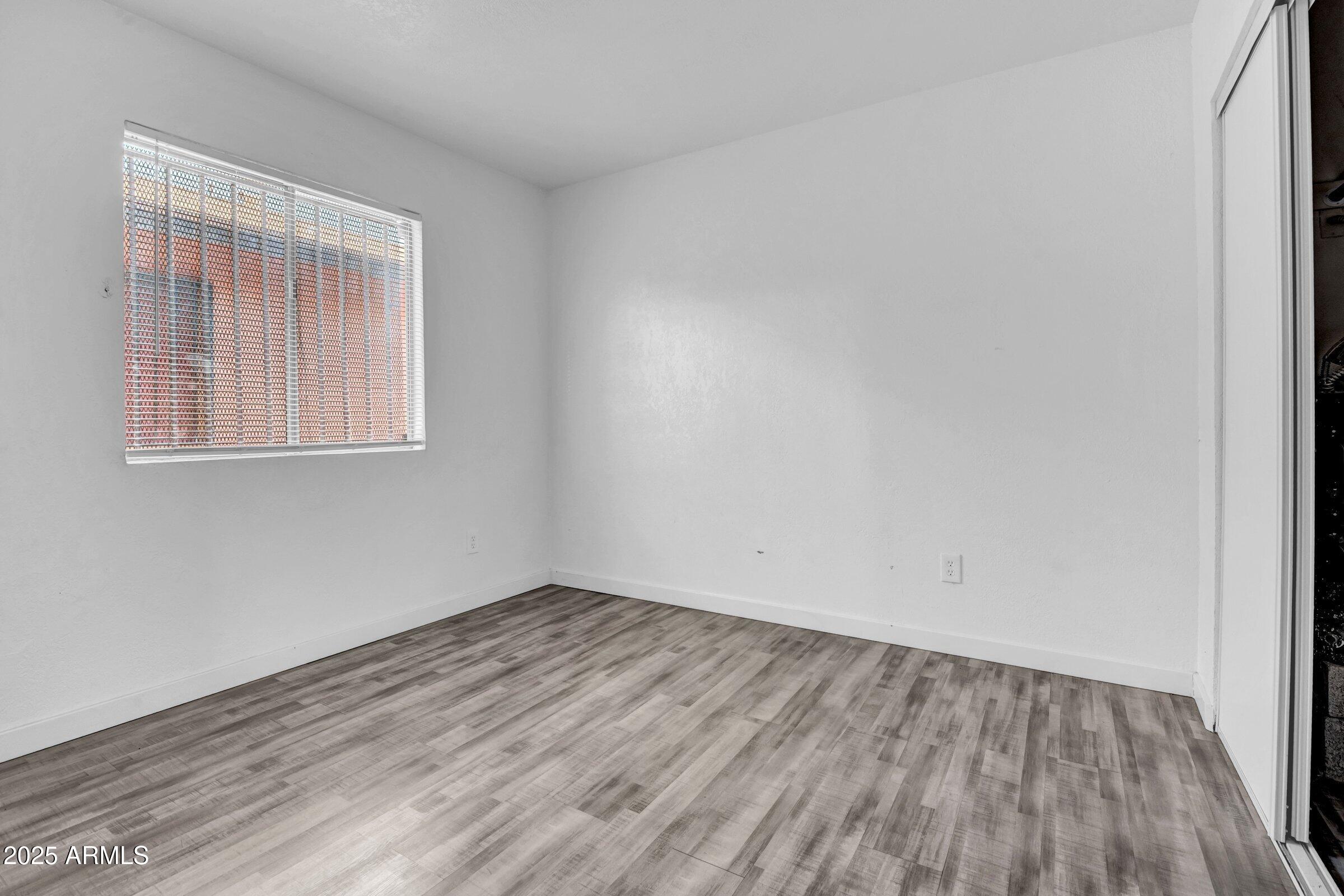 1123 West Fillmore Street Phoenix, AZ 85007 - Photo 13 of 20 an empty room with wooden floor and windows