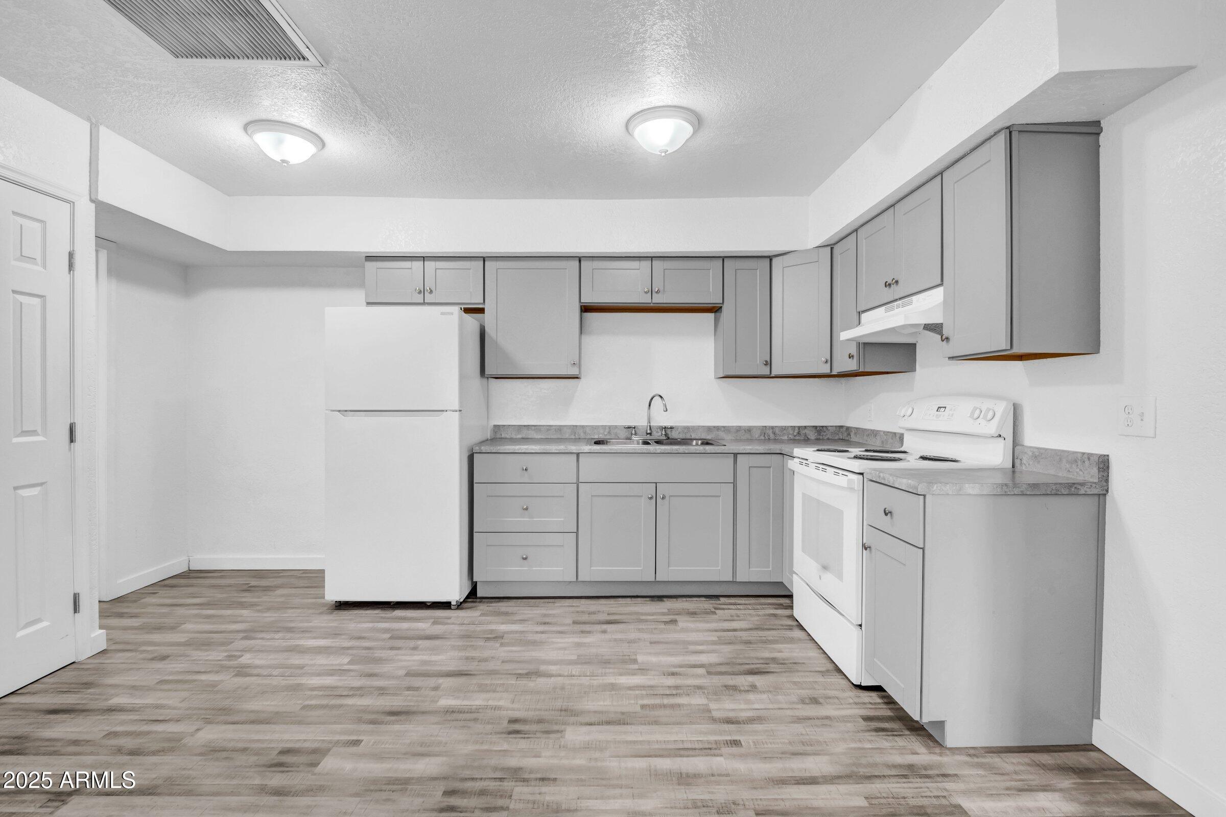 1123 West Fillmore Street Phoenix, AZ 85007 - Photo 6 of 20 a kitchen with white cabinets and white appliances