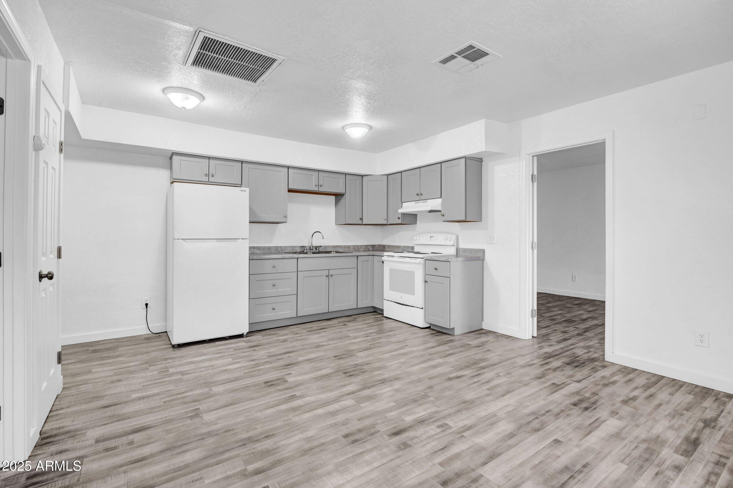 1123 West Fillmore Street Phoenix, AZ 85007 - Photo 7 of 20 a kitchen with a white cabinets and wooden floor