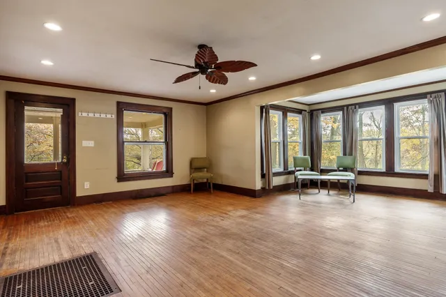 a view of empty room with wooden floor and fan