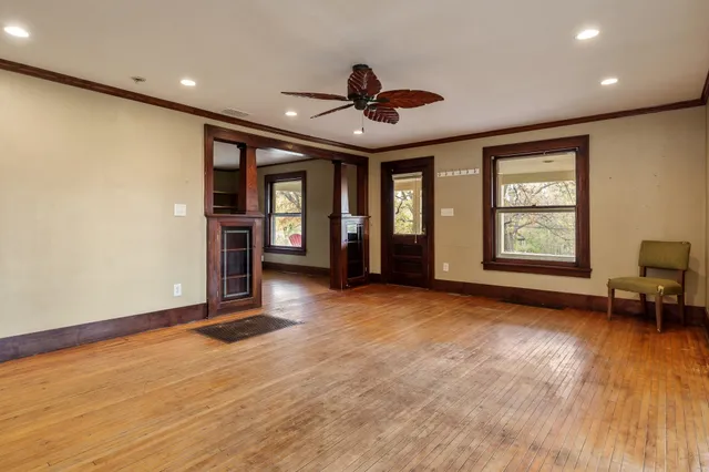 a view of an empty room with a window and wooden floor
