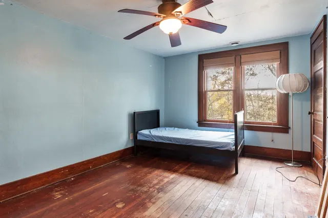 a bedroom with wooden floor and window