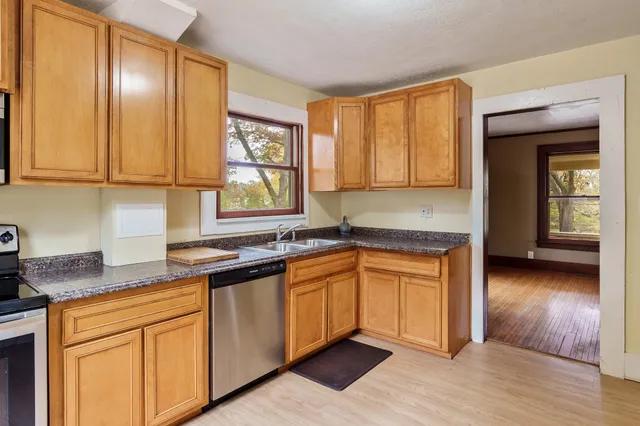 a kitchen with stainless steel appliances granite countertop wooden cabinets a sink and dishwasher with wooden floor