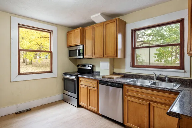 a kitchen with stainless steel appliances granite countertop a sink a stove cabinets and a window