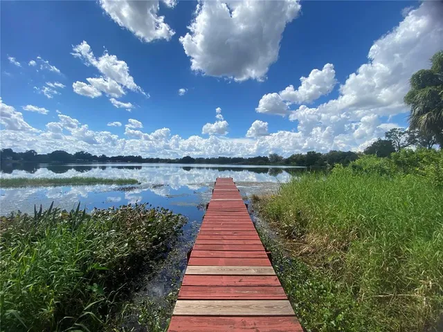 a park with lots of green space houses and lake in back