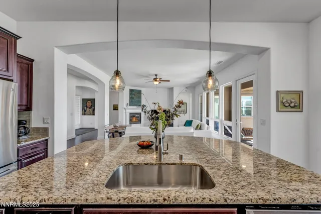 a kitchen with kitchen island granite countertop a sink a counter top space and living room view