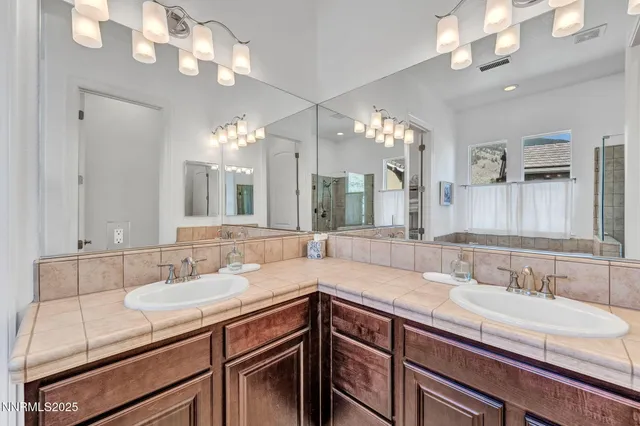 a bathroom with double vanity and a mirror